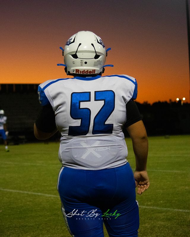 A lineman walking the field as the sun goes down behind the stand