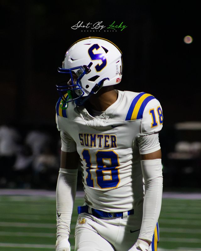 A receiver standing alone on the field, caught under the floodlights