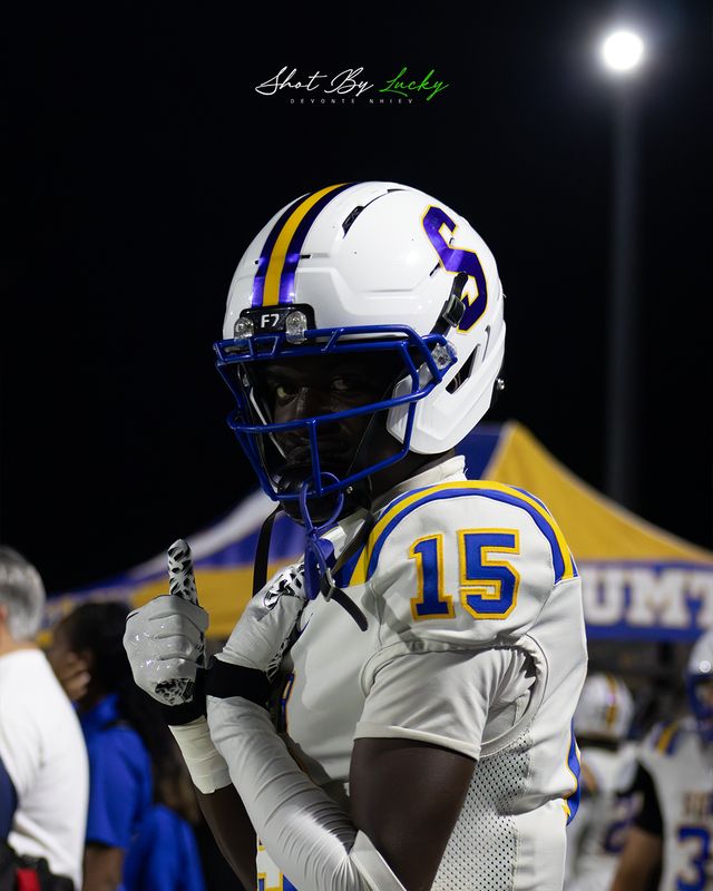 A player in his helmet with a floodlight burning behind him