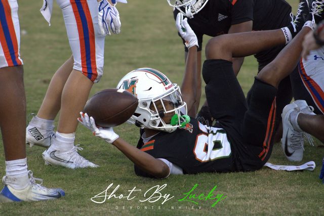 A player on his back holding the ball up through a crowd of legs