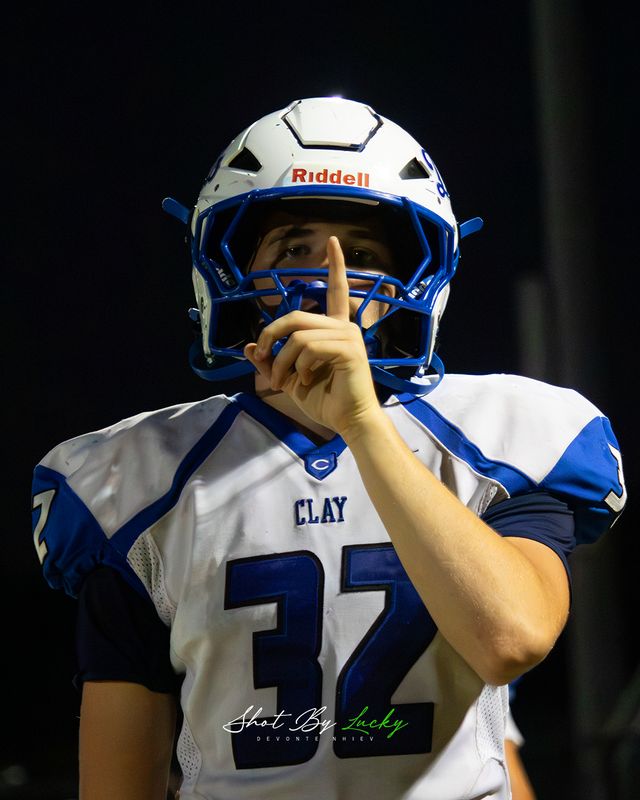A player with a finger to his helmet, quieting the other stand